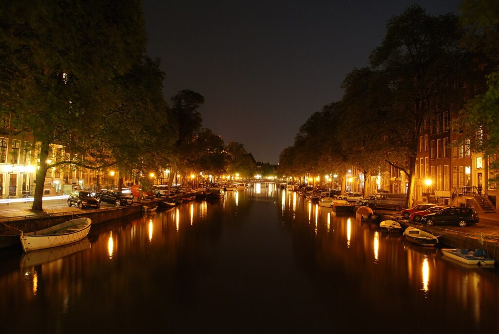 An Amsterdam canal lit up at night during Amsterdam Dance Event season