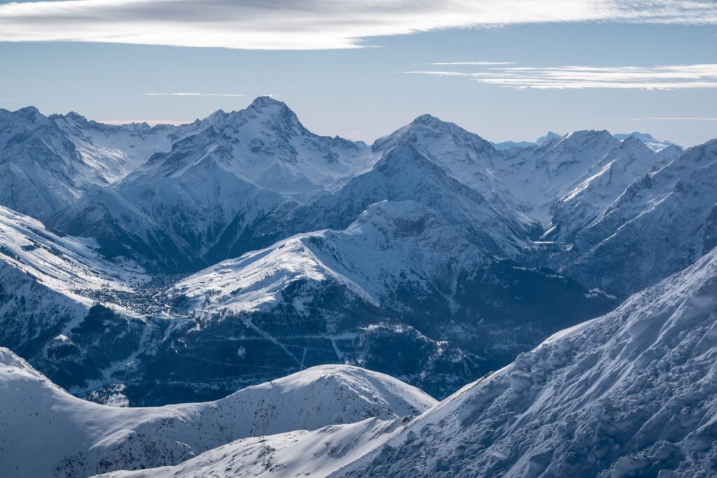 Snow-covered mountain ridges beneath a blue sky in Huez, France