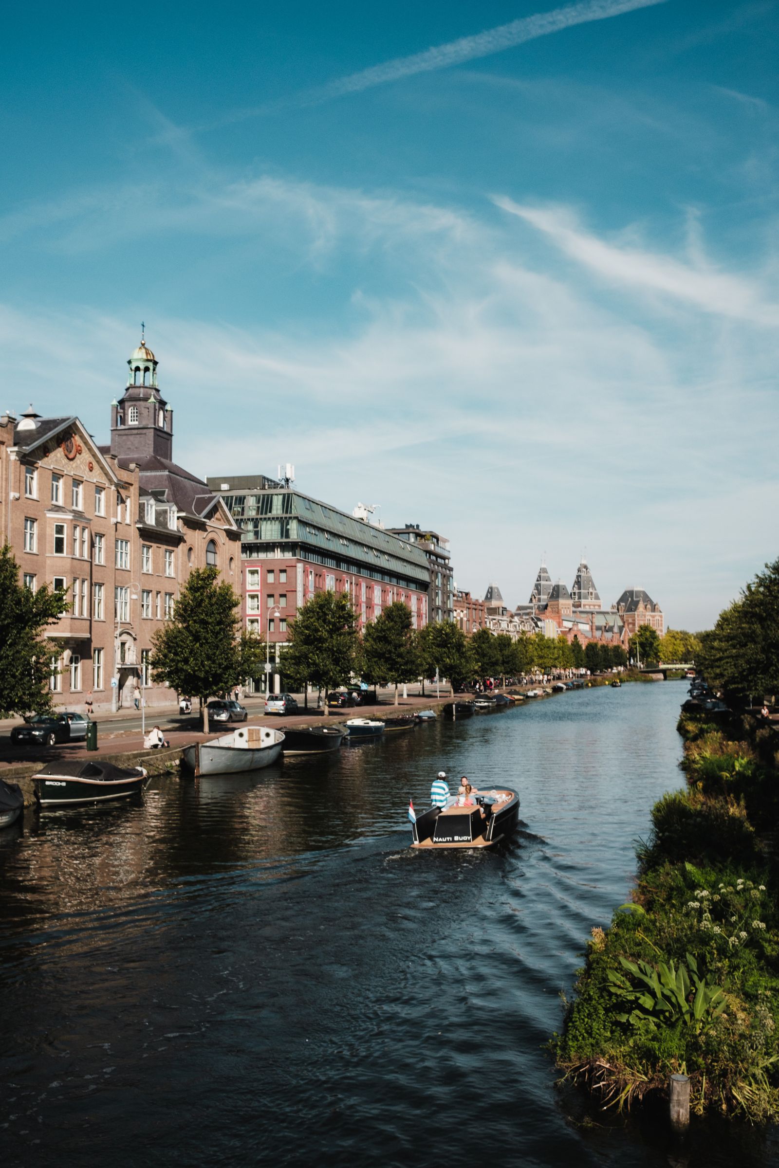 Amsterdam canal with boats, waterside buildings and a blue sky